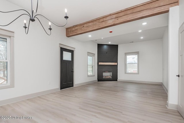 unfurnished living room featuring beamed ceiling, baseboards, light wood-style flooring, and a fireplace