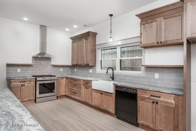 kitchen featuring stainless steel gas range, light wood-style flooring, a sink, black dishwasher, and wall chimney range hood