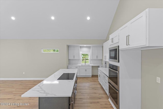 kitchen featuring built in microwave, oven, a kitchen island, and black electric cooktop