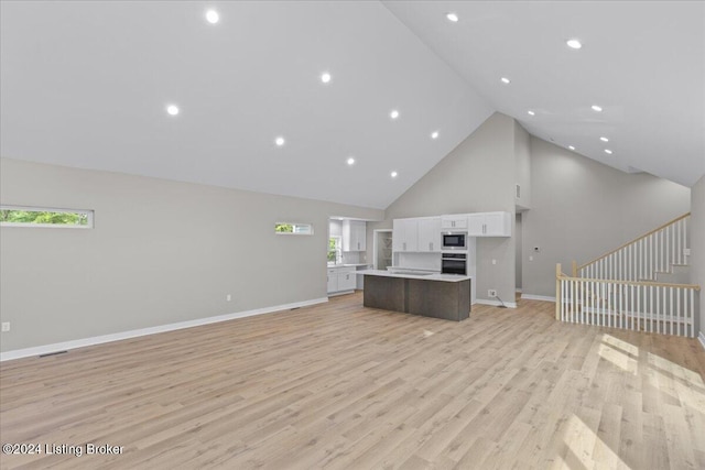 unfurnished living room featuring high vaulted ceiling, recessed lighting, baseboards, stairway, and light wood-type flooring