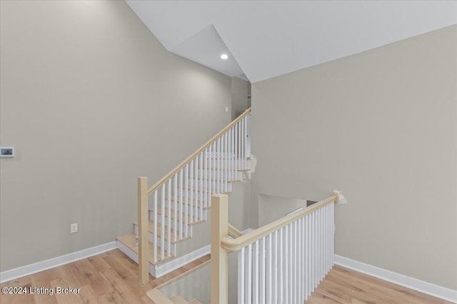 staircase with baseboards, wood finished floors, and recessed lighting