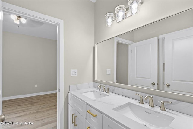 bathroom with double vanity, wood finished floors, a sink, and baseboards