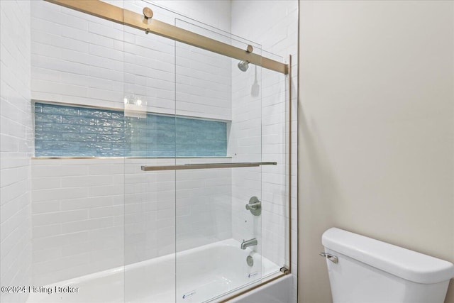 bathroom featuring toilet and combined bath / shower with glass door