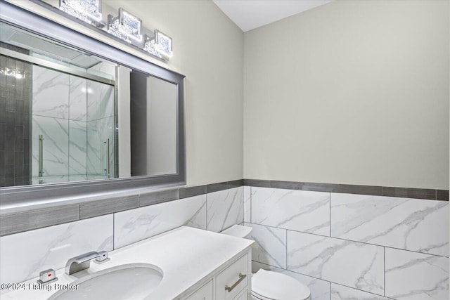 bathroom with toilet, a shower stall, tile walls, and vanity