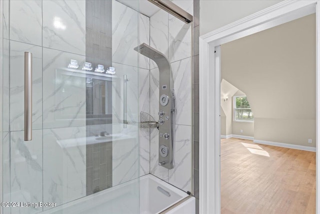 full bath featuring a shower with shower door, baseboards, and wood finished floors