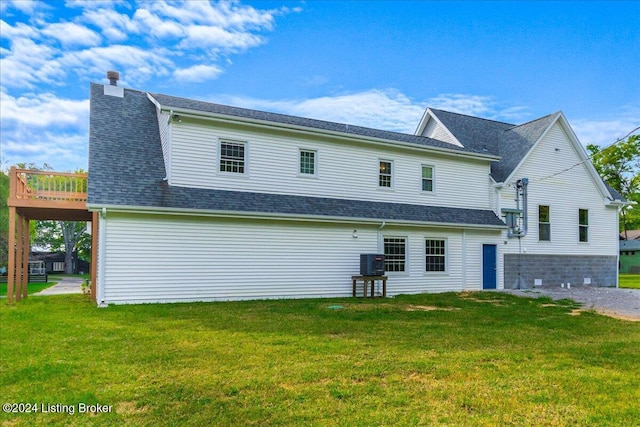 back of house featuring a yard, a shingled roof, and central AC