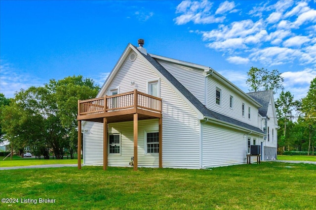 back of house featuring roof with shingles and a lawn