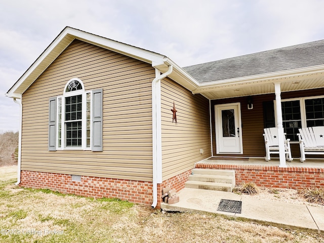 property entrance with a shingled roof, a porch, and crawl space