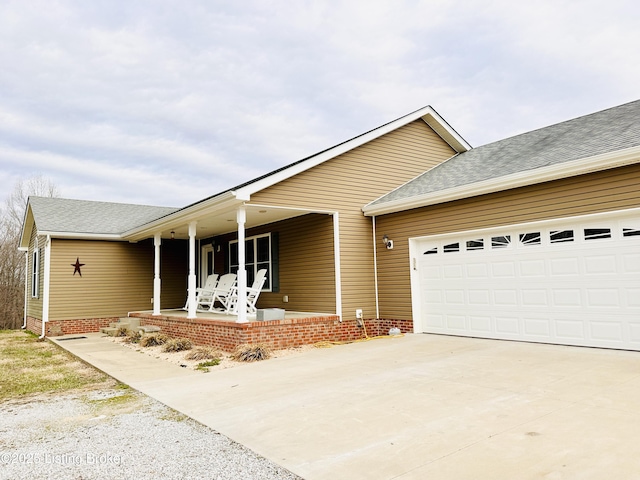 ranch-style home with a porch, driveway, a garage, and roof with shingles