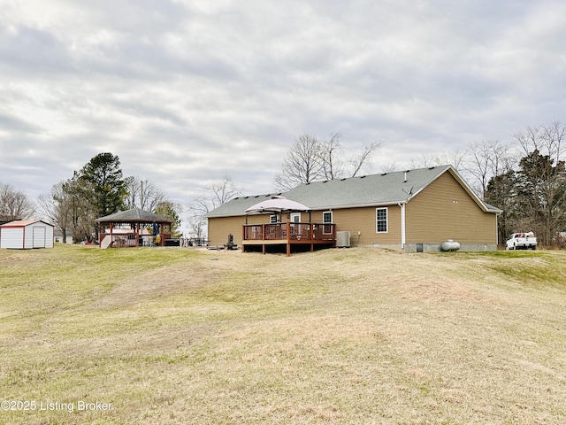 back of house featuring an outbuilding, a wooden deck, central AC, a gazebo, and a lawn