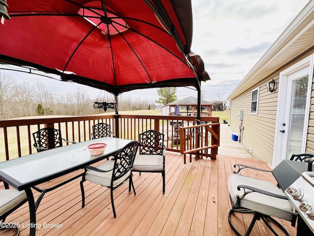 wooden terrace featuring a gazebo and outdoor dining area