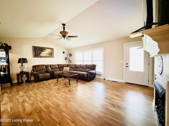 living area with baseboards, lofted ceiling, light wood-style floors, and a ceiling fan