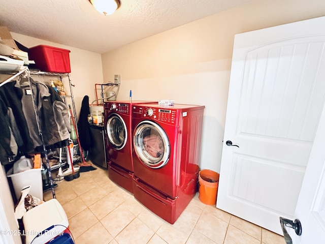 laundry room with light tile patterned floors, a textured ceiling, washing machine and dryer, and laundry area