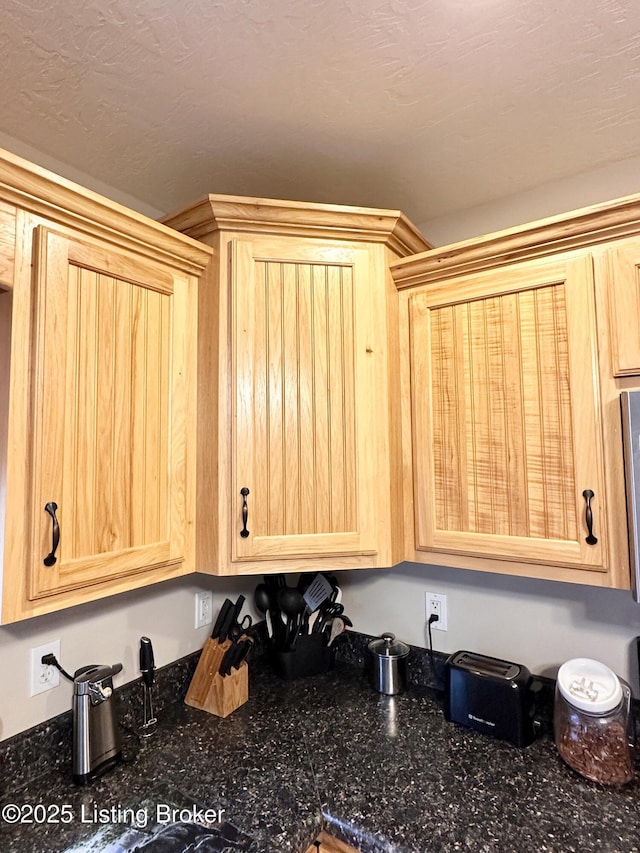 interior details featuring dark stone counters and light brown cabinets