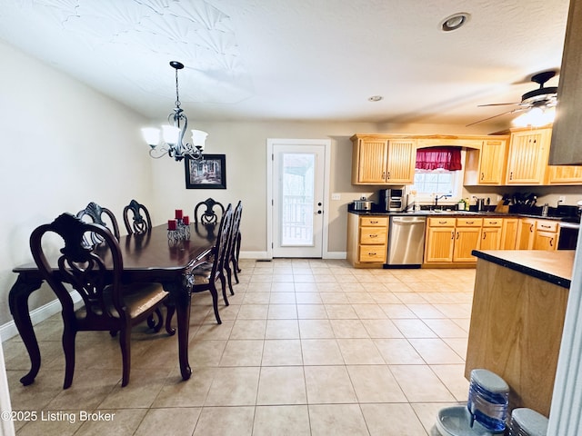 kitchen with pendant lighting, a sink, stainless steel dishwasher, dark countertops, and light tile patterned flooring