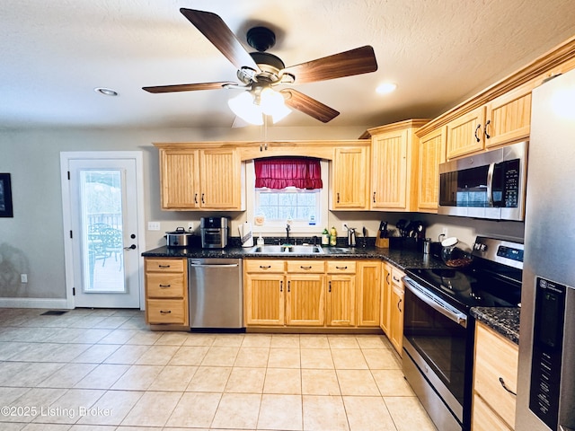 kitchen featuring light tile patterned floors, light brown cabinets, appliances with stainless steel finishes, and a sink