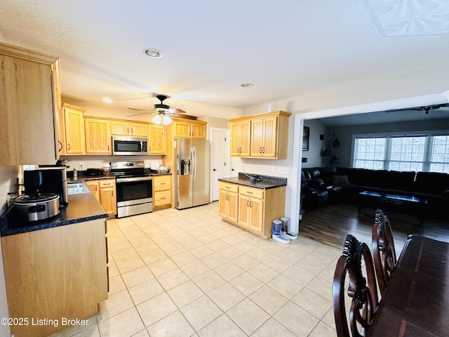 kitchen featuring dark countertops, appliances with stainless steel finishes, and light brown cabinetry