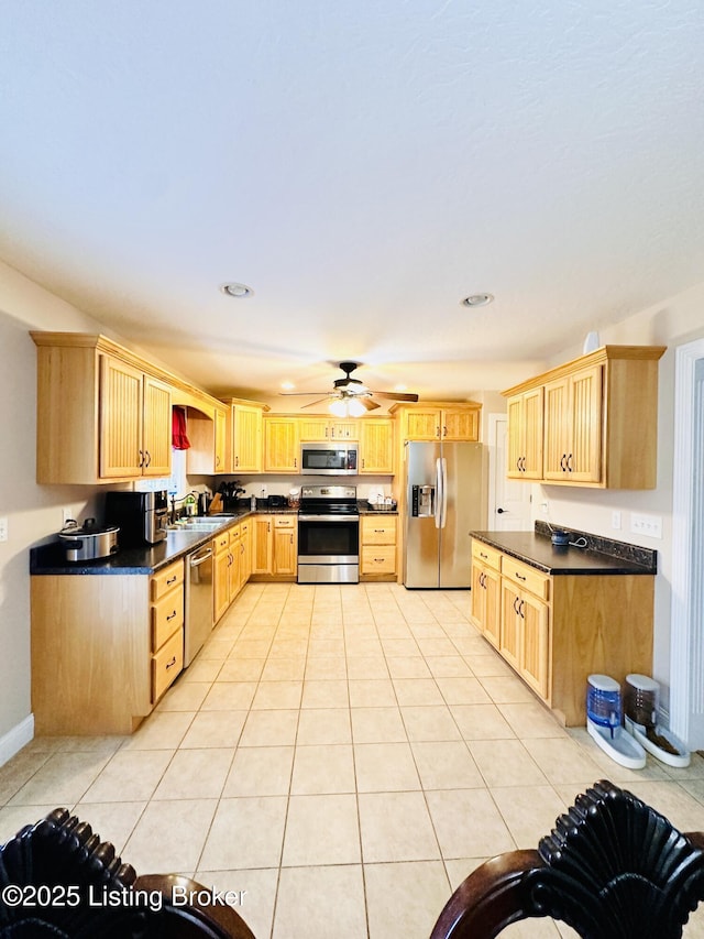 kitchen with light tile patterned floors, dark countertops, appliances with stainless steel finishes, and light brown cabinets