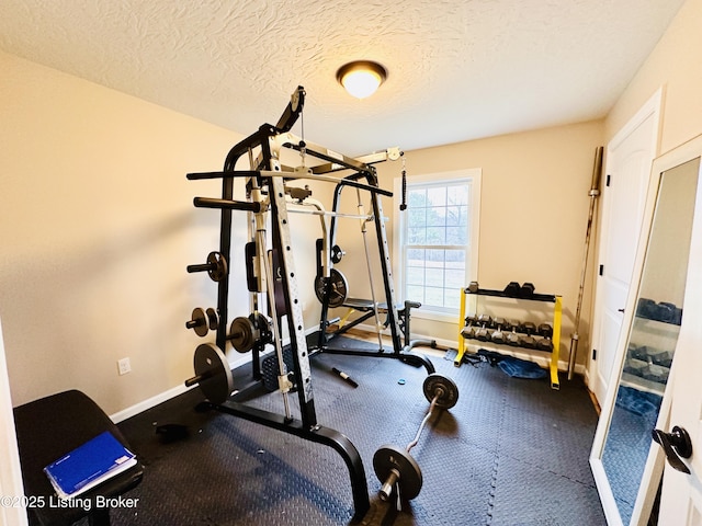 exercise room with baseboards and a textured ceiling