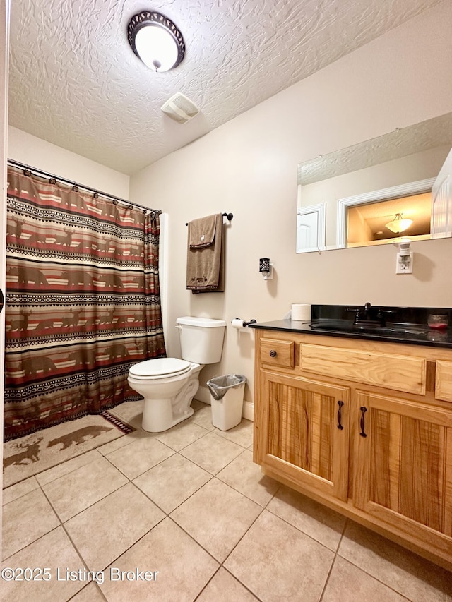 full bath featuring tile patterned flooring, curtained shower, toilet, vanity, and a textured ceiling