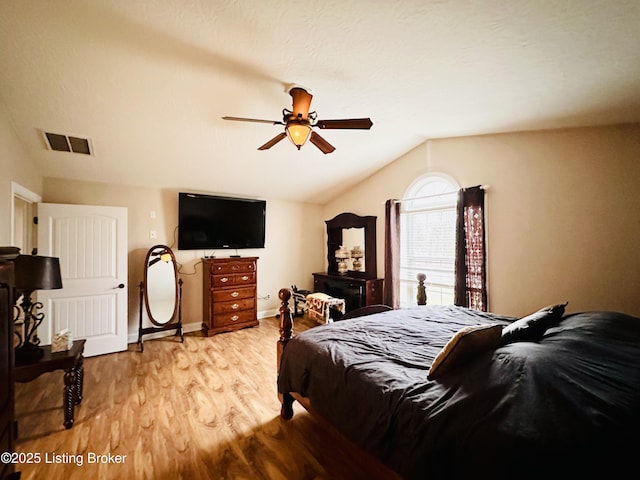 bedroom with visible vents, light wood-style flooring, baseboards, lofted ceiling, and ceiling fan