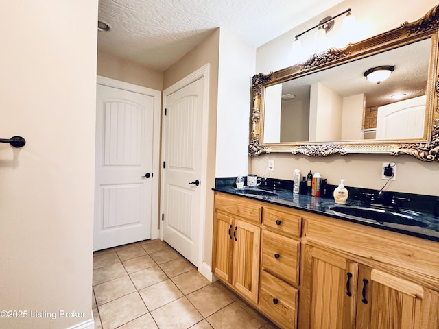 full bathroom with tile patterned floors, double vanity, a textured ceiling, and a sink