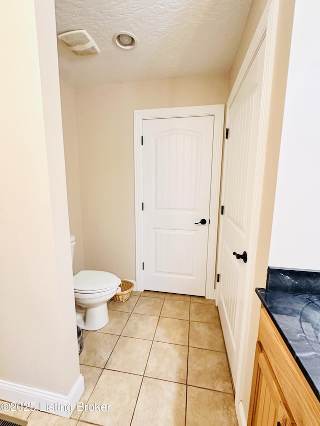 bathroom featuring tile patterned flooring, visible vents, baseboards, toilet, and a textured ceiling