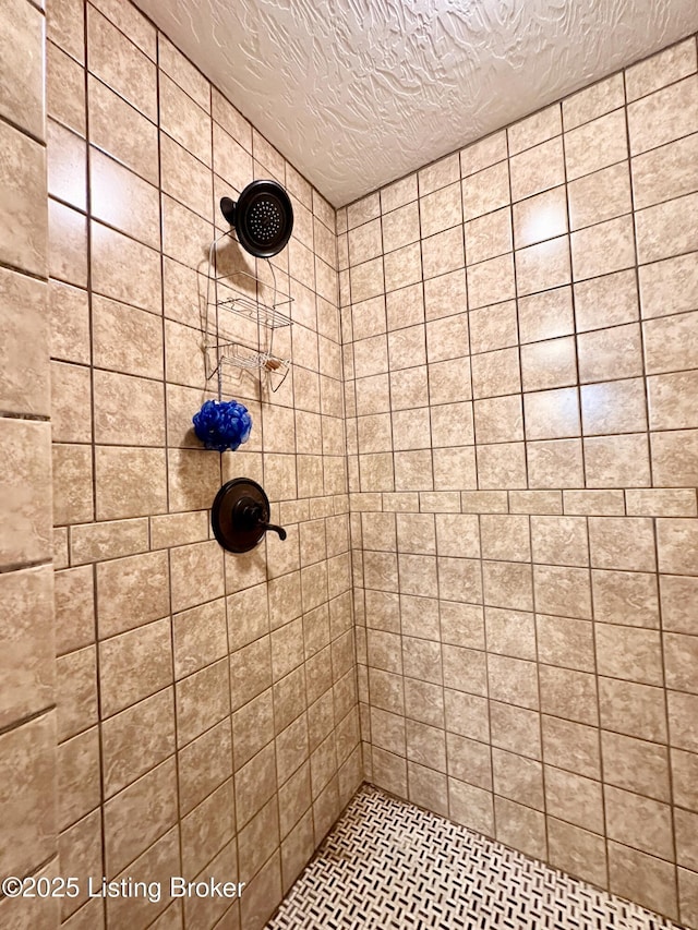 bathroom with a tile shower and a textured ceiling