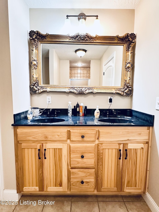 bathroom featuring double vanity, tile patterned floors, baseboards, and a sink