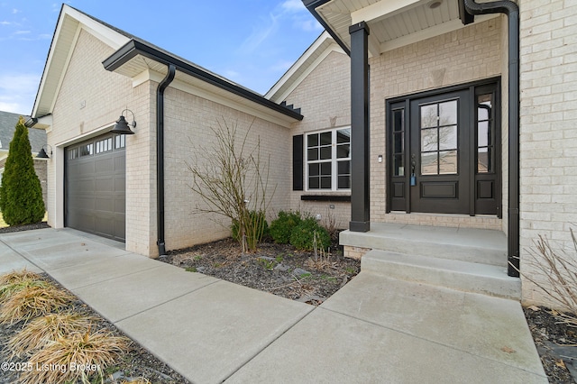 doorway to property with a garage and brick siding