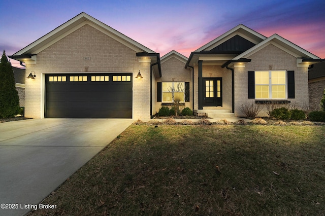 view of front facade with an attached garage, a lawn, concrete driveway, and brick siding