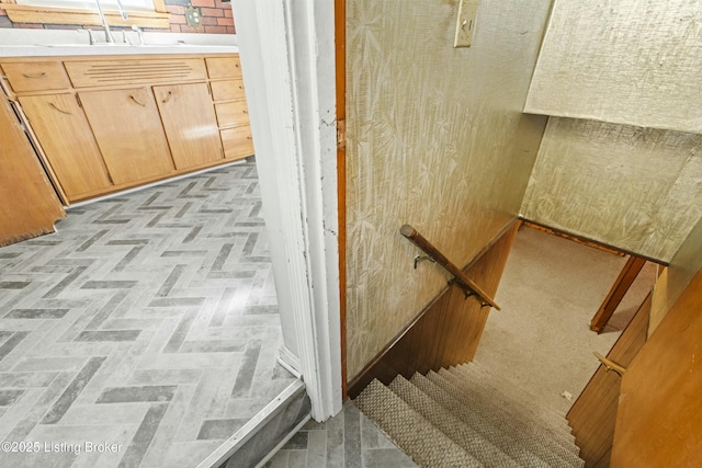 interior space with brick floor, a sink, and an upstairs landing