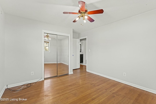 unfurnished bedroom featuring a ceiling fan, a closet, baseboards, and wood finished floors