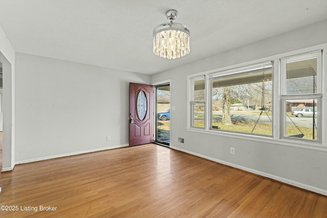 foyer featuring baseboards, wood finished floors, and an inviting chandelier