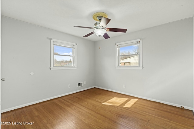 unfurnished room featuring ceiling fan, wood finished floors, visible vents, and baseboards