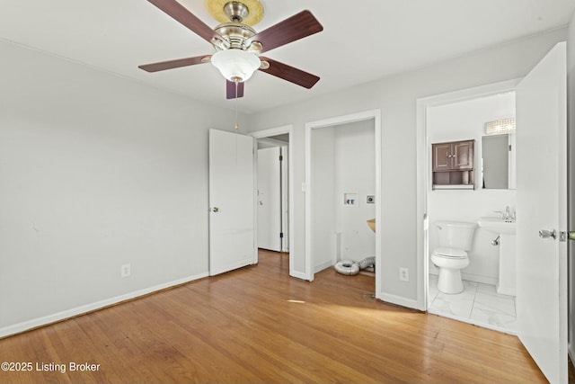 unfurnished bedroom featuring connected bathroom, baseboards, and wood finished floors