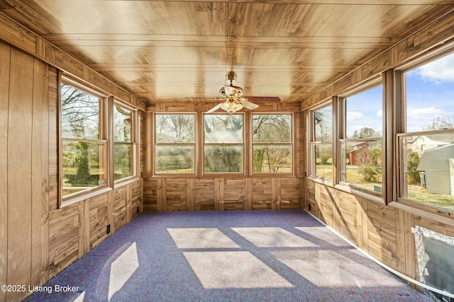 unfurnished sunroom featuring plenty of natural light, wood ceiling, and ceiling fan