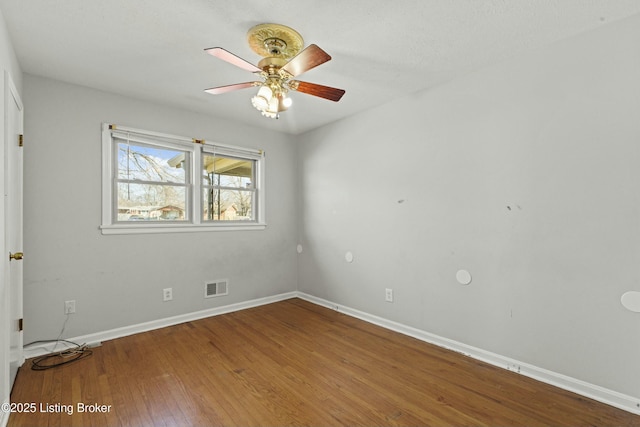 empty room featuring baseboards, visible vents, ceiling fan, and hardwood / wood-style floors