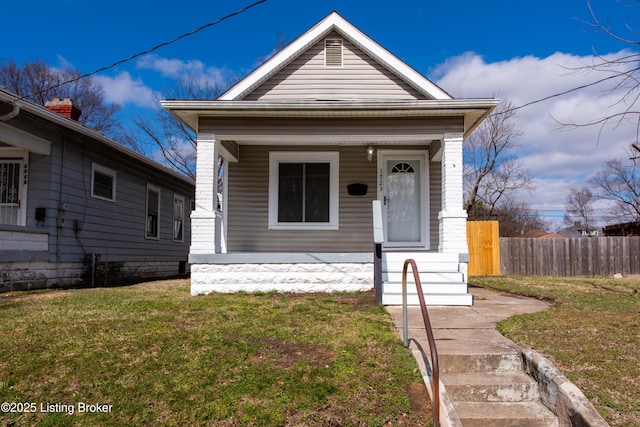 shotgun-style home with covered porch, fence, and a front yard