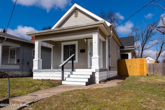 shotgun-style home with a shingled roof, a gate, fence, a porch, and a front yard