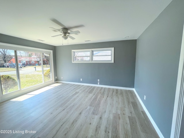 spare room featuring light wood-style floors, visible vents, baseboards, and a ceiling fan