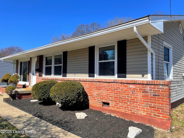 view of front of house with crawl space, covered porch, and brick siding