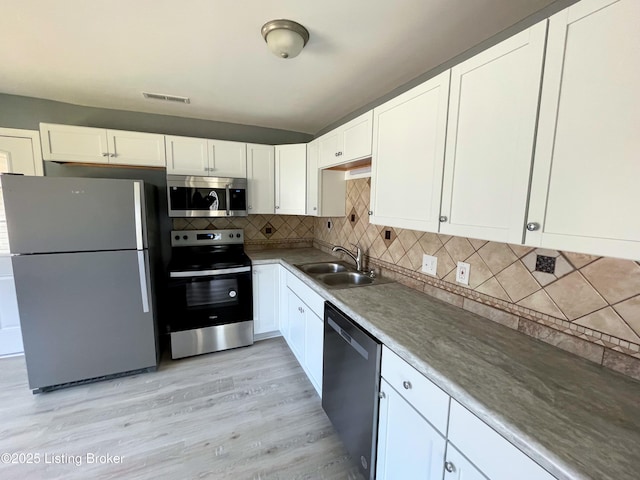 kitchen featuring stainless steel appliances, a sink, visible vents, white cabinets, and backsplash