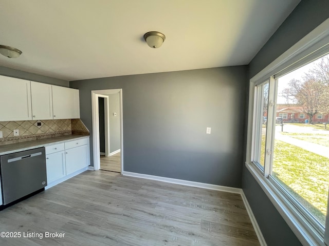 kitchen with tasteful backsplash, baseboards, white cabinets, and stainless steel dishwasher