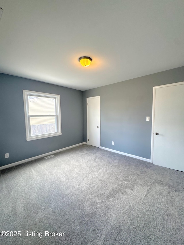 carpeted spare room featuring baseboards and visible vents