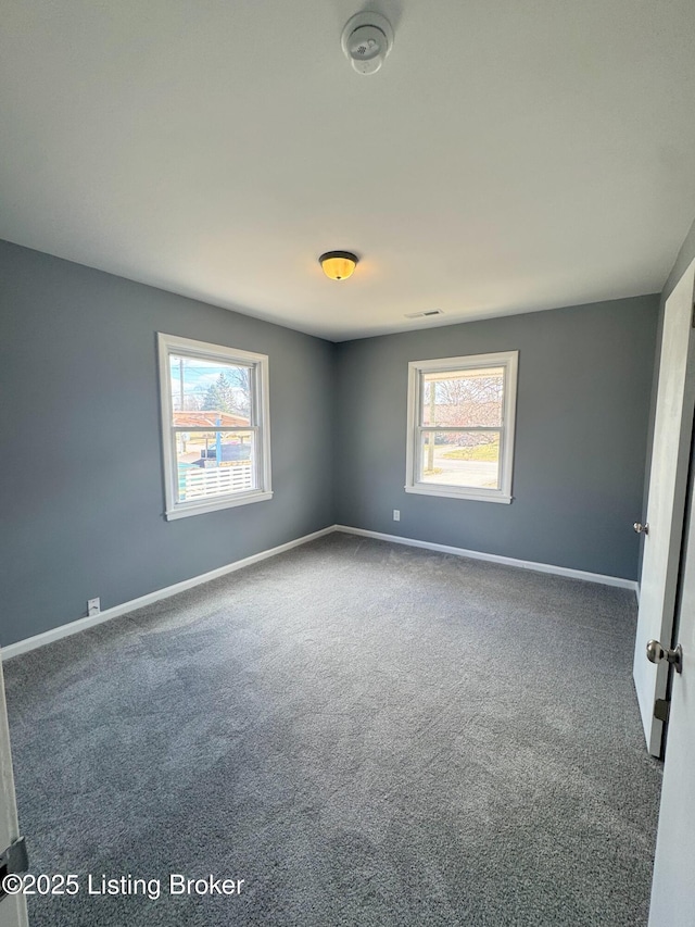 unfurnished room featuring carpet and baseboards