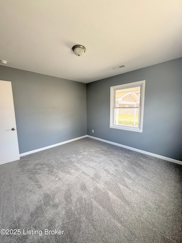 empty room with carpet, visible vents, and baseboards