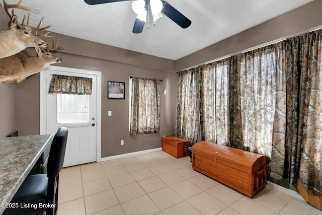 interior space with light tile patterned flooring, ceiling fan, and baseboards