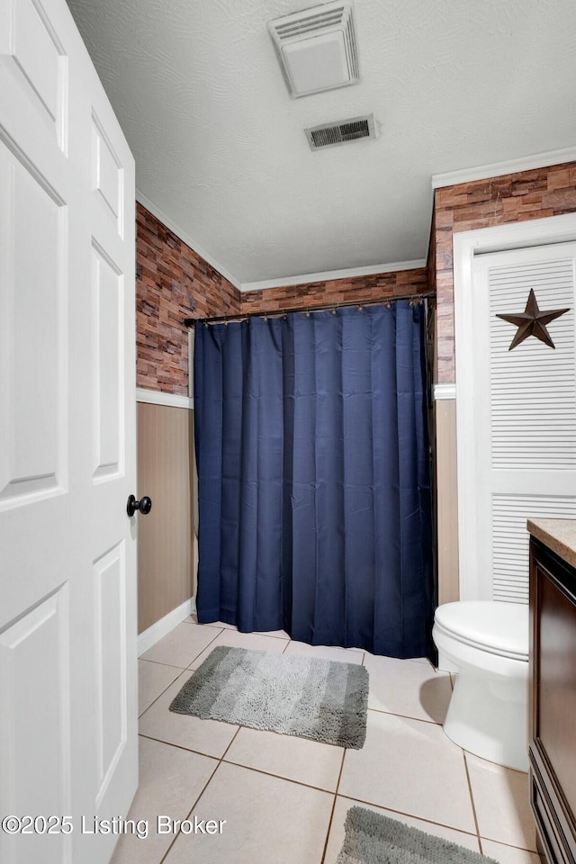 full bath featuring tile patterned flooring, wainscoting, and visible vents