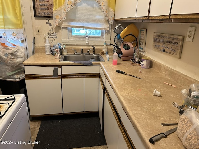 kitchen featuring light countertops, range, a sink, and white cabinetry